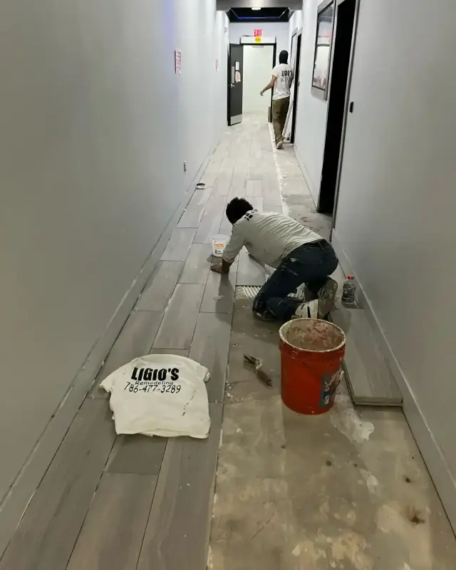 Ligio's Solutions team member installing new flooring in a building hallway