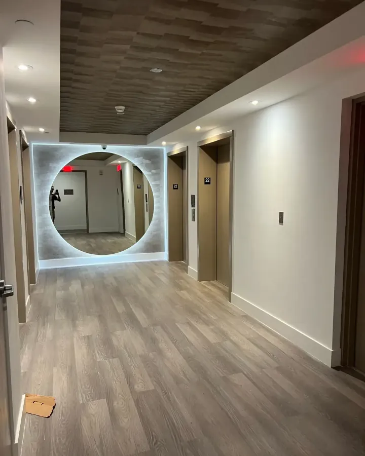 Elevator lobby with a large circular backlit mirror and new floors, renovated by Ligio's Solutions in Hollywood, FL